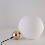 The Soul Table Lamp - Gold is a modern desk lamp with a large frosted white glass globe and a smaller gold sphere, joined by a black power cord, displayed against a plain white background.