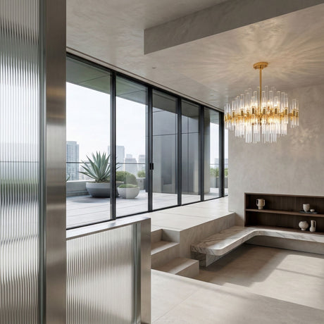 A modern, minimalist living space with floor-to-ceiling windows, a marble bench, open shelves, a Chiara 15 Light Crystal Chandelier - Gold for luxurious lighting, and a terrace with a potted plant overlooking the city skyline.