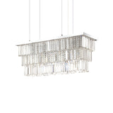 The Fluxon 6 Light Crystal Suspension - Chrome features a rectangular arrangement with three tiers of dangling glass prisms, producing a sparkling effect. Supported by three thin cables, this chrome fixture shines brilliantly against the plain white background.