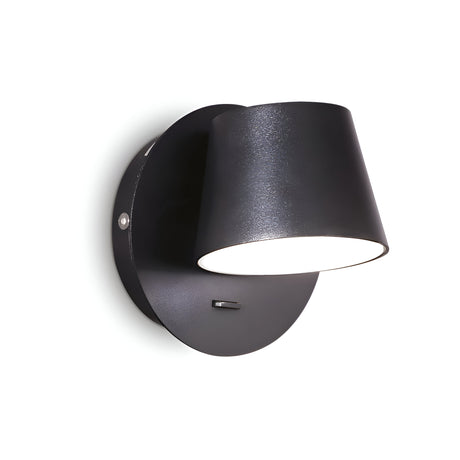 The Gim LED Wall Light 6W 3000K in black boasts a contemporary design with a matte finish, featuring a circular base and conical shade that directs light downward. Its sleek and minimalist aesthetic fits seamlessly into modern interiors, providing ambient lighting that stands out beautifully against a white background.