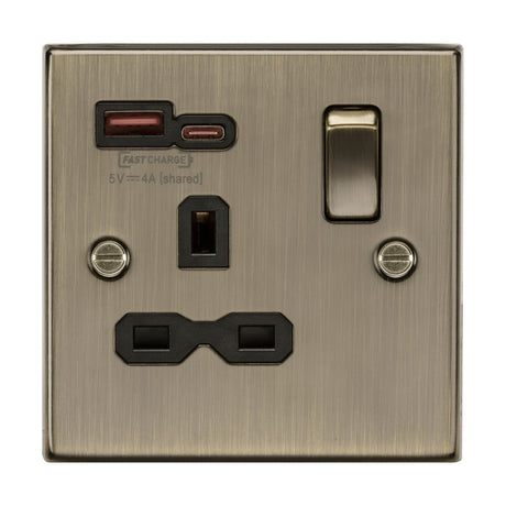 A UK standard wall outlet in antique brass, featuring a single 13A socket with a black insert, dual USB ports for FASTCHARGE (USB-A and USB-C) supporting PD and QC charging, and a switch on the right side.