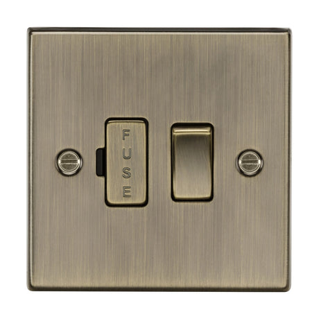 The 13A Switched Fused Spur Unit in antique brass (square edge) features a brushed metal texture and built-in fuse holder. It is a double pole switch secured with two visible screws, blending functionality and style effortlessly.