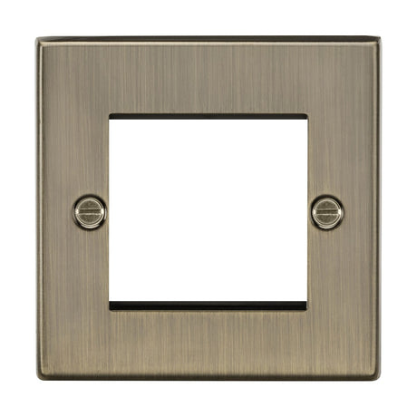 The 2 Gang Modular Faceplate in antique brass has a square edge, with a brushed bronze finish, central square cutout, and two visible screws on either side.