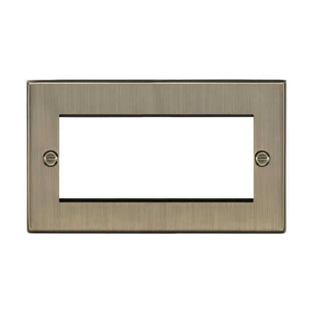 The 4 Gang Modular Faceplate - Antique Brass is a rectangular, brushed metal cover featuring a central opening for a rectangular switch. It has an antique brass finish and includes two screw holes, one on each side for easy mounting. This faceplate combines a sleek, modern design with a touch of vintage charm.