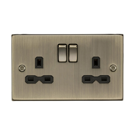 An antique brass double electrical socket with a square edge design and double pole switches, featuring twin earths and black inserts. Ideal for both home and office, it blends modernity with elegance.