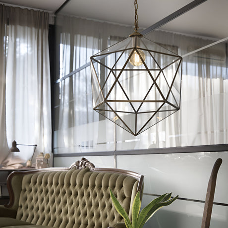 The stylish room features the Verdant 1 Light Large Pendant in a brass finish, hanging from the ceiling amidst frosted glass panels. Positioned below is a green tufted sofa, complemented by a plant placed to the right. Soft natural light gently filters through sheer curtains that cover the expansive windows.