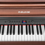 Close-up of the NU-X NCK-430 weighted digital piano in walnut, showing the control panel with colour display, dials, function buttons and weighted keys.