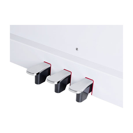Close-up of the NU-X NCK-330 digital upright piano's three chrome-topped assignable pedals with red trim, mounted on the white base.