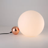 The Soul Table Lamp - Copper is a modern minimalist lamp featuring a large glowing white orb and a smaller metallic copper sphere on a plain white base, complete with a black power cord.
