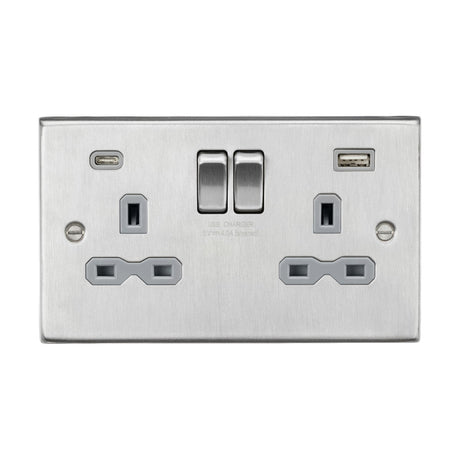 The 13A 2 Gang SP Switched Socket With Dual USB A+C, featuring a brushed chrome finish and grey insert with a square edge design, includes two standard power outlets alongside a dual USB charger with one USB-A and one USB-C port. Two switches are conveniently located above the outlets to effectively control power flow.