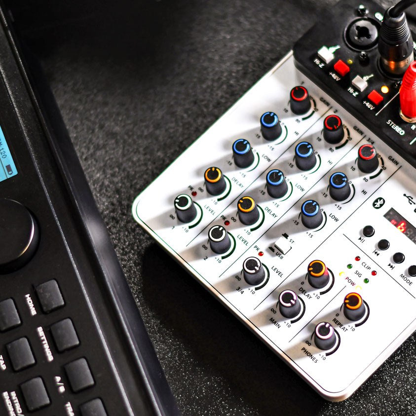 Citronic Q-PAD compact mixer by AVSL on a desk, showing colour-coded gain, EQ and delay knobs, USB and Bluetooth controls, beside a MIDI controller.