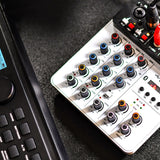 Citronic Q-PAD compact mixer by AVSL on a desk, showing colour-coded gain, EQ and delay knobs, USB and Bluetooth controls, beside a MIDI controller.