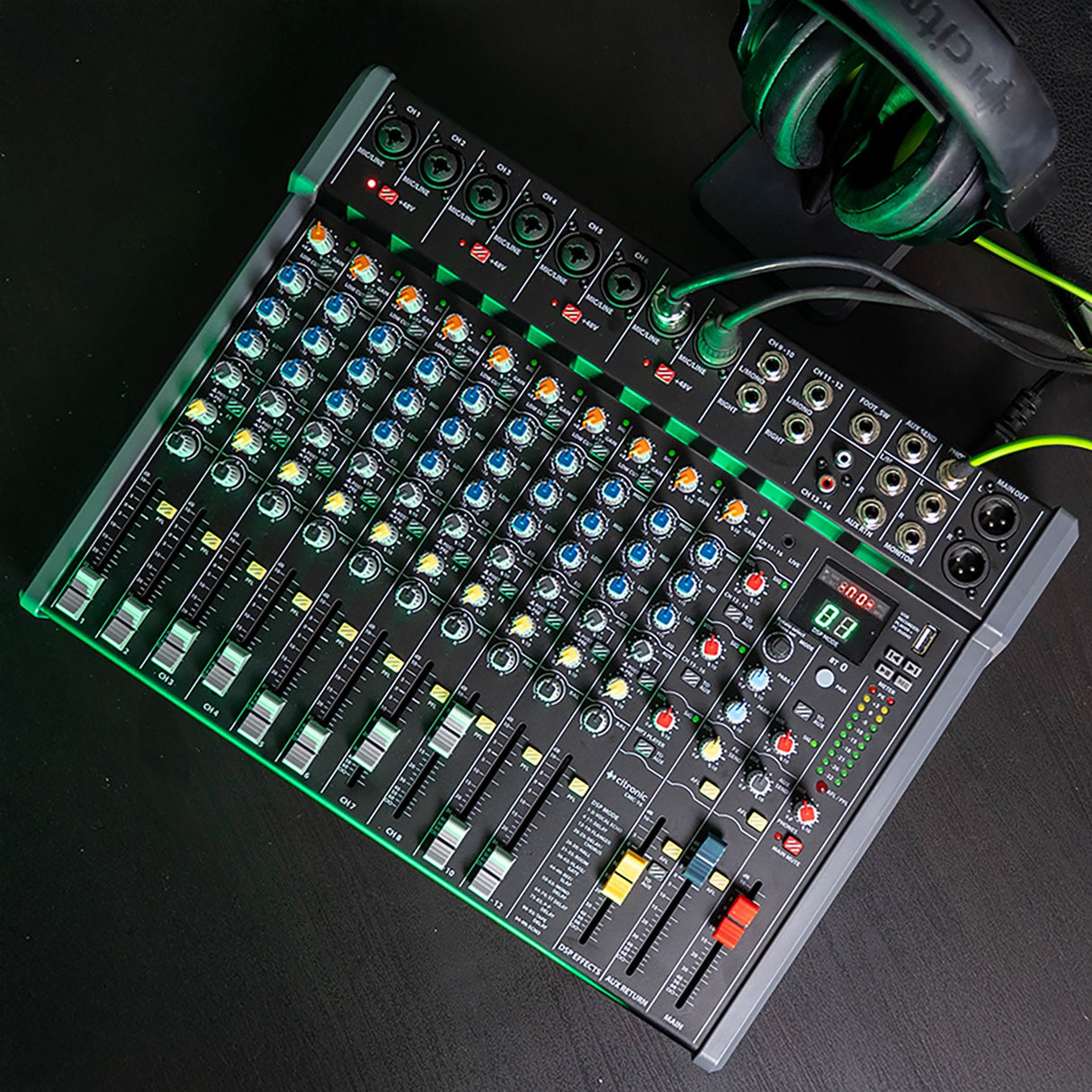 Citronic CMC-16 live mixing console with multiple channel faders, rotary EQ knobs, DSP display and XLR inputs, shown beside green headphones on a dark surface.