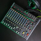 Citronic CMC-16 live mixing console with multiple channel faders, rotary EQ knobs, DSP display and XLR inputs, shown beside green headphones on a dark surface.