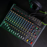 Citronic CMC-18 live mixing console with multiple channel faders, EQ knobs, DSP display and USB port, shown on a dark surface with headphones.