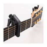Cherub CGC-1 Gemini adjustable guitar capo in matte black clamped to an acoustic guitar fretboard near the headstock with gold tuners.
