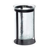 Libra Interiors Hammered Glass Black Iron Hurricane Lantern with a clear textured glass cylinder set in a slim black iron frame on a round base.