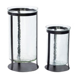 Libra Interiors Hammered Glass Black Iron Hurricane Lanterns shown in two sizes, with clear cylinders set in slim black iron frames on round bases.