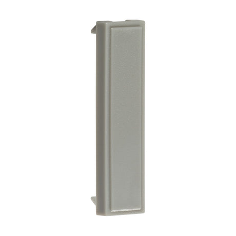 A gray, rectangular object made of plastic with ABS construction, featuring smooth surfaces and a slightly raised edge on one side, similar to modular faceplates, is displayed vertically against a white background. This is part of a pack of 10 Quarter Blanking Modules measuring 12.5 X 50mm each.