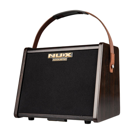 NU-X AC-25 portable 25W acoustic guitar amplifier with dark wood cabinet, black speaker grille, gold logo and brown leather carry strap.