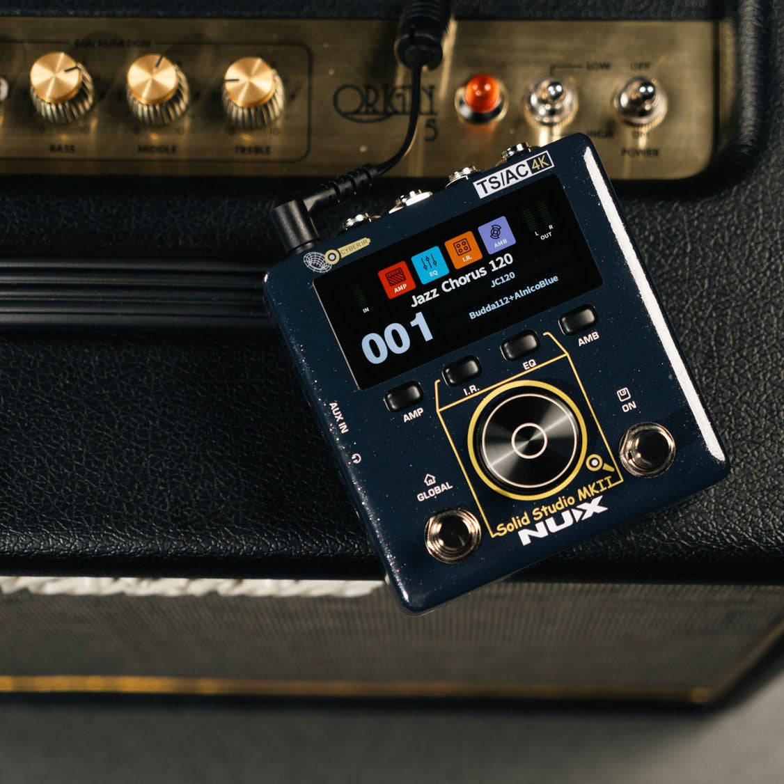 NU-X NSS-6 Solid Studio mkII amp and cab emulation pedal in dark blue with colour display showing Jazz Chorus 120 preset, resting on a guitar amp.