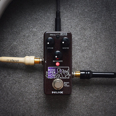 NU-X NCH-5 Mini Super Chorus-Flanger Modulation Pedal in dark sparkle finish with Speed, Width, Intensity knobs and footswitch, connected on a grey surface.