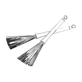 Line-drawn illustration of Chord WBRUSH retractable wire drum brushes crossed as a pair with black plastic handles and fanned wire bristles.