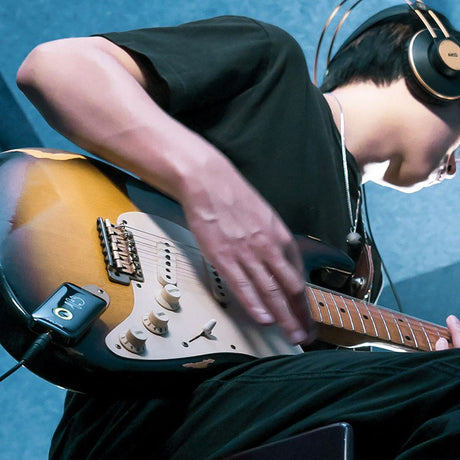 NU-X MP-2 Mighty Plug Bluetooth headphone amp by AVSL plugged into a sunburst electric guitar as a player in headphones practises.
