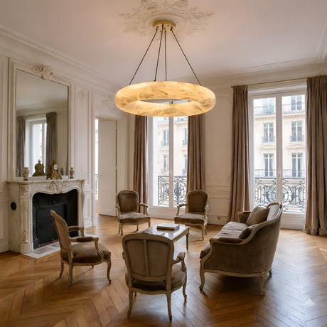 Elegant living room with ornate molding, marble fireplace, large windows with taupe curtains, vintage armchairs and sofa around a coffee table, and a striking Calviro LED Large Ring Alabaster Chandelier - Soft White on the ceiling.