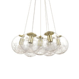 The Lyria 7 Light Cluster Pendant - Brass features a contemporary style with its seven glass spheres. Inside each sphere is a nest of silver wires, all elegantly suspended by delicate wires and highlighted by a brass finish, bringing sophistication to any room.