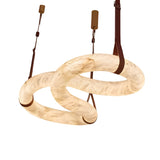 The Serava LED Medium Alabaster Asymmetric Suspension Light in Brown & Soft White features a modern twisted ring design with brown straps and ceiling mounts, illuminated against a white backdrop.