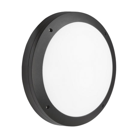 The 18W Outdoor CCT LED Bulkhead with Microwave Sensor - Black features a sleek, round design with a smooth, flat white face and a matte finish. This IP65-rated fixture combines modern minimalism with its circular frame and four visible screw holes for easy mounting, crafted from anti-vandal polycarbonate for improved durability.
