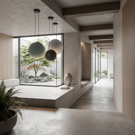 A minimalist interior with neutral tones highlights the Cosmos 3 Light LED Bar Pendant - V1, complemented by a potted fern, a decorative vase, and wide windows overlooking a serene Japanese-style garden with rocks and greenery.