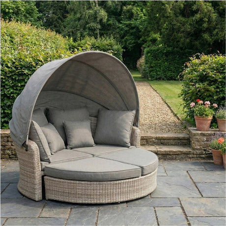 Sandy Beige Bermuda Day Bed Garden Furniture Set, 160cm round rattan daybed with retractable canopy and grey cushions, shown on a garden patio.