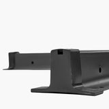 Steel parasol cross base, 6cm tall, matte black finish with a T-shaped cross bar and square centre socket, shown close-up on a plain white background.