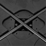 Close-up of the Steel Parasol Cross Base in matte black, showing the crossed steel poles and moulded base sections joined with visible screws.