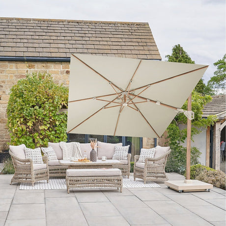 Challenger Teak T2 3.5m rectangular cantilever parasol in champagne with wood-effect frame, shading a rattan garden sofa set on a stone patio.
