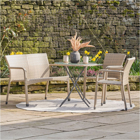 Tobs Outdoor Grey Synthetic Rattan Bistro Set with a two-seat bench and two armchairs around a round glass-top table on a garden patio.