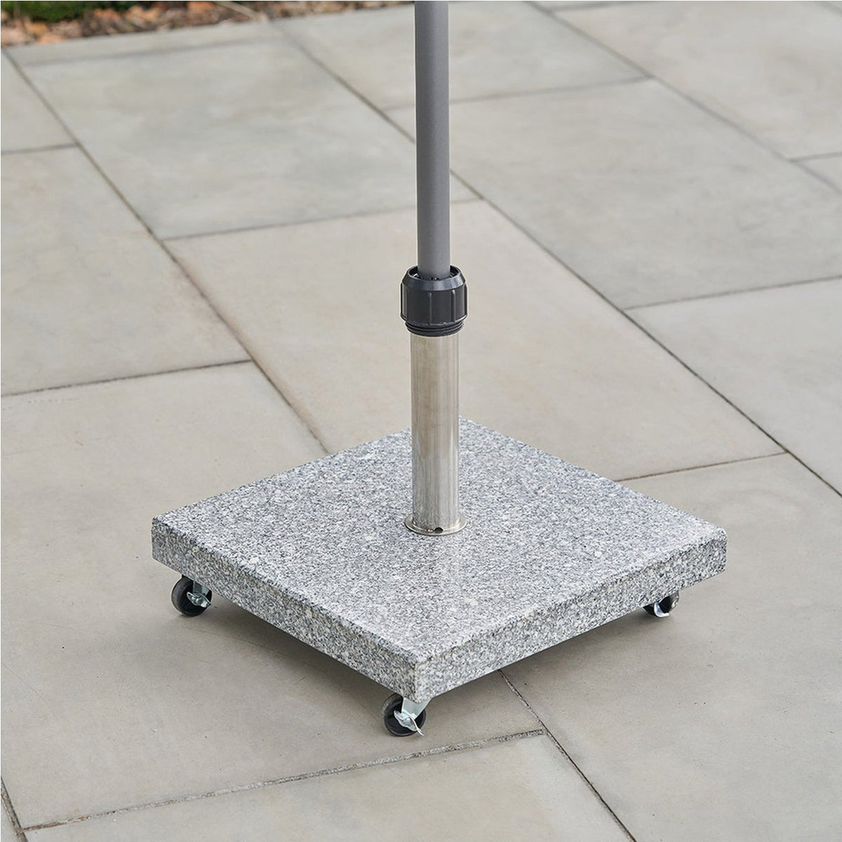 Salerno Hammered Grey wheeled parasol base in square granite-effect stone with castor wheels, supporting a stainless steel and grey pole on an outdoor patio.