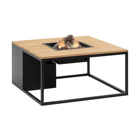 Cosi Black & Teak Gas Fire Pit Table, 100cm square with black metal frame and teak-effect top, centre burner alight with logs, on a plain white background.