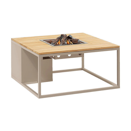 Cosi Sandy Beige & Teak Gas Fire Pit Table, 100cm, with square teak tabletop, beige metal frame, and stainless steel burner with ceramic logs and flame, on a plain white background.