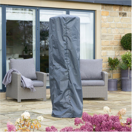 Cylinder Patio Heater Aerocover in anthracite fabric fitted over an outdoor heater on a patio, shown beside grey rattan sofas near a stone house exterior.