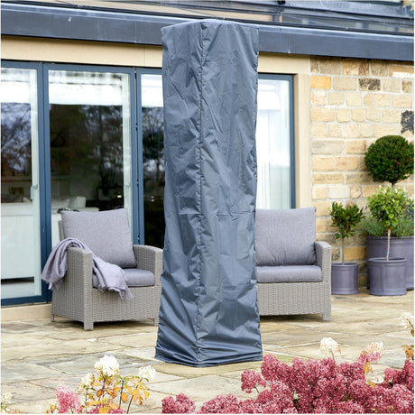 Anthracite grey fabric Quadrilateral Patio Heater Aerocover (52 x 45cm) fitted over a tall standing patio heater on a garden patio beside rattan armchairs.