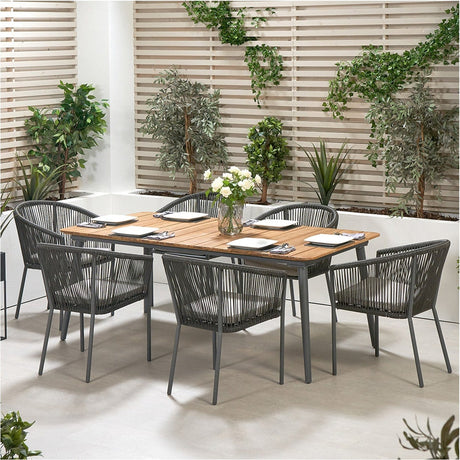 Reims Outdoor Dining Set with wood-effect table and six grey woven aluminium chairs, set on a patio against a slatted wood screen and greenery.