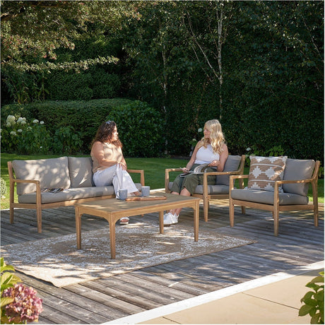 Beige Acacia Outdoor Seating Set on a garden deck, with wooden-framed sofa and armchairs, beige cushions, patterned cushion, and matching wood coffee table.