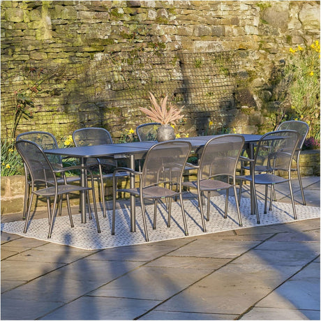 Carlo Extendable Rectangular 8 Seater Dining Set in grey steel, with mesh-back chairs around an extendable table, set on a garden patio against a stone wall.