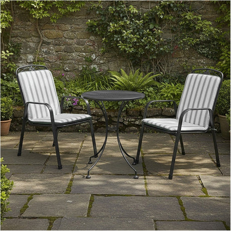 Savoy Bistro Set with two black metal chairs featuring grey striped cushions and a round mesh table, shown on a stone patio against a garden wall.