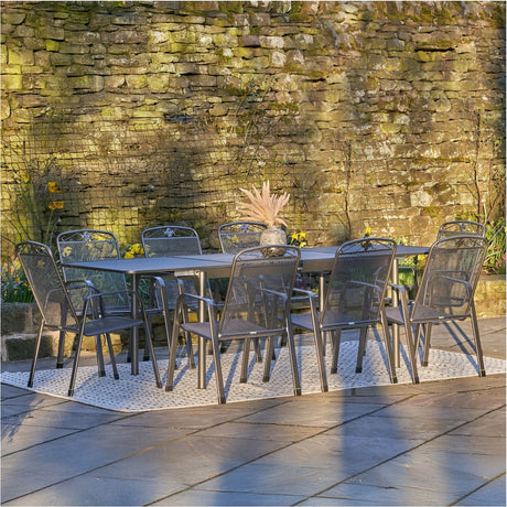 Savoy Extendable Rectangular 8 Seater Dining Set in iron grey steel, mesh-back chairs around a rectangular table, set on a patio against a stone wall.