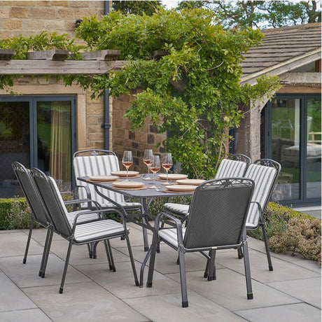 Savoy Rectangular 6 Seater Dining Set with grey striped cushions on stackable metal chairs, set on a patio with a rectangular table and glassware.