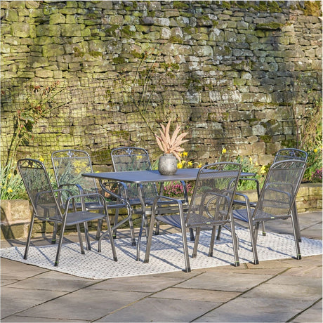 Savoy Rectangular 6 Seater Dining Set in grey steel, rectangular table with mesh-back chairs, set on a patio against a stone wall.
